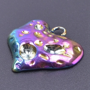 Macro view of a rainbow heart pendant featuring an irregular hammered crater texture