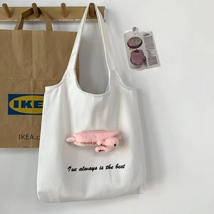 Detailed close-up of white canvas tote bag with pink rabbit plush and art text