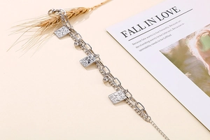 Detail of silver double-layer chain bracelet with card pendants and metal beads