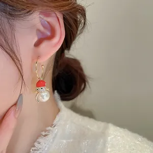 Detail of Christmas snowman earrings with red enamel hat and pearl body on a model