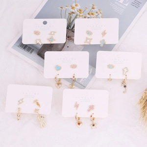 Macro detail of gold-plated copper earrings with zircon cross and heart designs