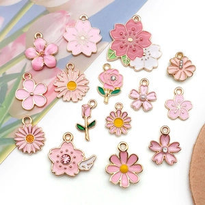 Flat lay of pink and white enamel flower charms with gold plating for jewelry making