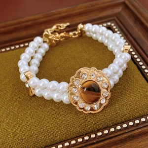 Dettaglio del braccialetto di perle vintage con chiusura a fiore in pietra occhio di tigre