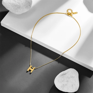 Detail view of double-layer stainless steel gold necklace with H pendant and 18KGP mark