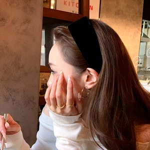 Plush black velvet wide headband shown on model in a stylish cafe setting