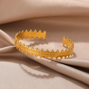 Close-up of gold stainless steel bangle with grid texture on champagne silk
