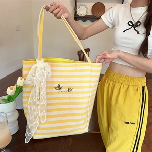 Close-up of yellow striped canvas tote with lace bow charm and butterfly embroidery