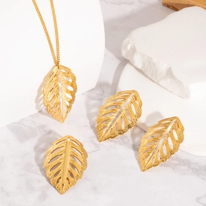 Ensemble collier et boucles d'oreilles doré avec feuilles évidées sur marbre