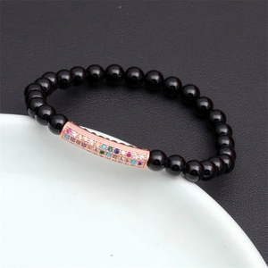 Macro shot of obsidian beaded bracelet with rose gold zircon tube on leather and ceramic