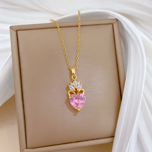 Elegant gold crown heart necklace with pink stone and zircons on beige jewelry box