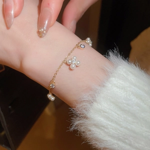 Detail of elegant gold bracelet with pearl flowers and sparkling zircon charms on wrist