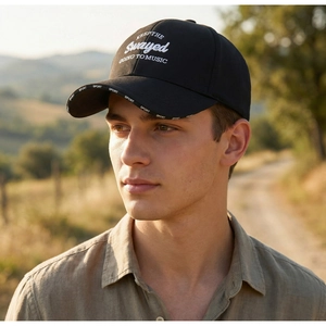 Outdoor male model wearing black baseball cap with white embroidery in golden hour light