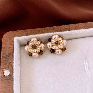 Close-up of vintage gold-plated earrings with pearls, brown gemstones, and zircon details