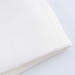 Detailed macro view of white woven fabric texture and stitched edge of the two-piece set