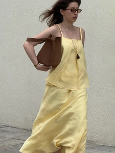 Yellow cotton-linen two-piece set featuring camisole and fishtail skirt with brown bucket bag