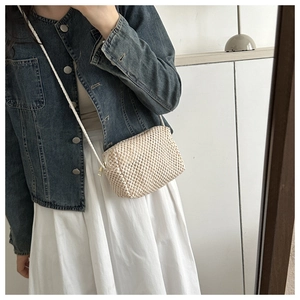 Detailed texture of a cream handmade woven mini crossbody bag shown in a casual outfit