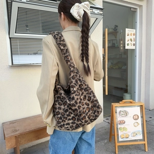 Outdoor shot of a fuzzy leopard print tote bag with wide straps on a model's shoulder