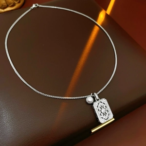 Close-up of a silver zircon hollow square pendant necklace on dark leather texture