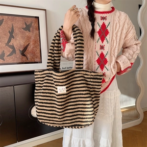 Detail of plush tote bag showing black and beige stripes with a woven logo label
