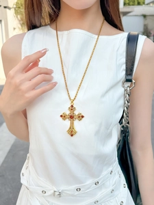 Gros plan du collier croix dorée vintage avec pendentif en pierre rouge sur un mannequin