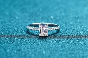 Macro shot of 1 carat emerald cut moissanite ring with side accent diamonds
