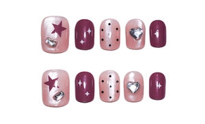 Macro detail of cat-eye press-on nails with stars, hearts, and rhinestones in pink and purple