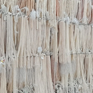 Esposizione verticale di fili di perle d'acqua dolce nei colori bianco, rosa e crema