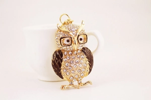 Macro de porte-clés chouette avec strass étincelants et lunettes dorées sur bureau blanc