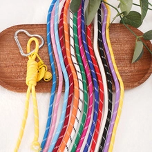 Colorful woven lanyards with silver heart buckles and bells on a wooden tray