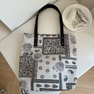 Bohemian paisley print cotton linen tote bag with black leather handles on white surface