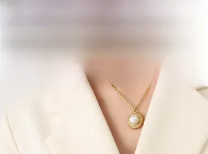 Close-up of pearl pendant necklace with twisted gold ring on a professional model