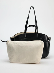 Detail of black leather tote bag with a beige canvas zipper pouch insert for organization