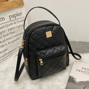 Quilted black mini backpack with gold zippers and hardware on a soft fur background