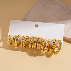 Detail view of 12-piece gold geometric earring set on card with stone texture background