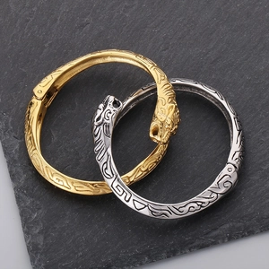 Detailed view of silver and gold tiger head bracelets on a textured slate surface