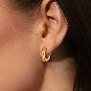 Macro shot of gold textured hoop earrings with a vintage croissant style pattern