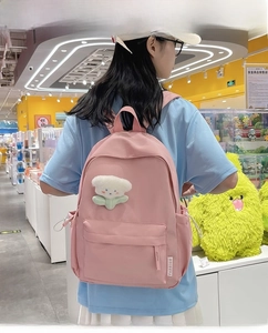 Detailed shot of pink backpack with floral plush charm and fashion woven label decoration