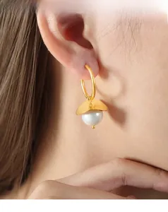 Detail of vintage French style gold hoop earrings with matte metal and large white pearls