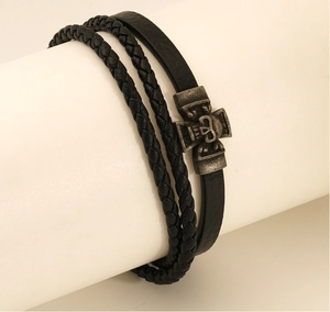 Detail eines mehrlagigen schwarzen Lederarmbands mit einem Vintage-Metall-Totenkopf-Charm