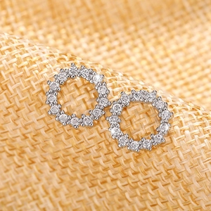 Macro shot of silver circular stud earrings with shimmering rhinestones on woven fabric