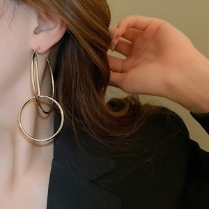 Exaggerated silver geometric double hoop earrings worn by a model in profile view