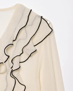 Dettaglio delle balze in chiffon beige con elegante bordo nero a contrasto cucito