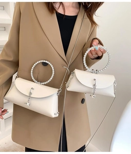 White leather handbag with rhinestone ring handle and silver chain fringe on beige suit