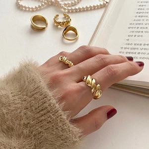 Detailed view of minimalist gold rings with twisted textures and smooth glossy finishes