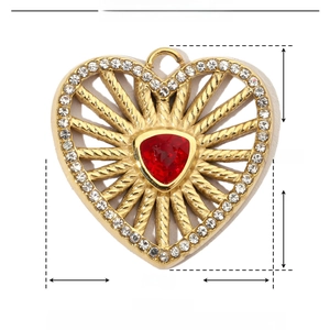 Macro shot of gold stainless steel heart pendant with red zircon and crystal detail