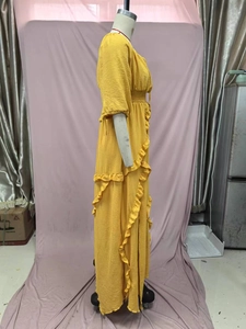 Detail of yellow tiered ruffle dress featuring pleated fabric texture and side layers