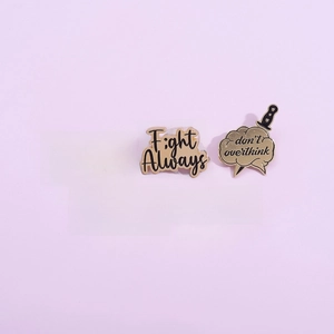 Five gold and black enamel quote pins with inspirational phrases on pink background