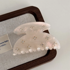 Macro shot of starry rhinestone embellishments on a cream acetate hair claw clip
