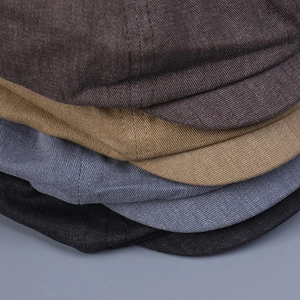 Detailed view of stacked vintage cotton flat caps in four colors showing twill texture