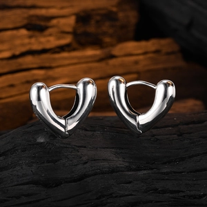 Polished V-shaped heart silver hoop earrings displayed on a dark charcoal wood base